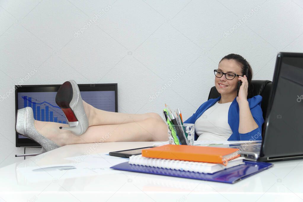 Relaxed and winning business woman sitting with her legs on desk