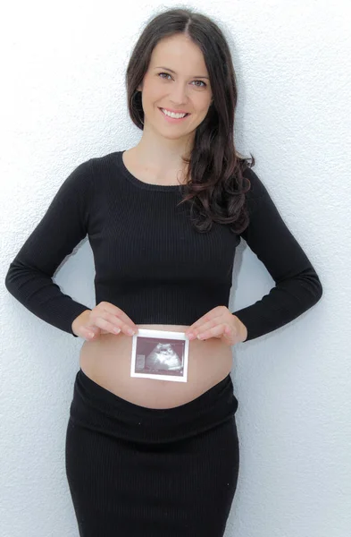 Gelukkig zwangere vrouw met grote buik bij het raam, zwangerschap, moeder — Stockfoto