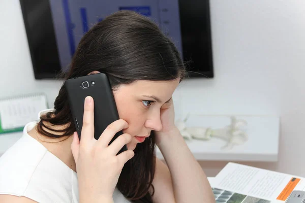 Atractiva mujer de negocios usar el teléfono inteligente y sentarse en su varita —  Fotos de Stock