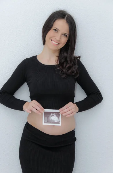 Gelukkig zwangere vrouw met grote buik bij het raam, zwangerschap, moeder — Stockfoto