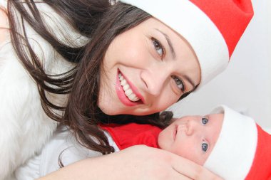 Mutlu anne ve erkek bebek Noel şapkası takıyor.