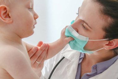 One year old sick baby boy at the young female doctor