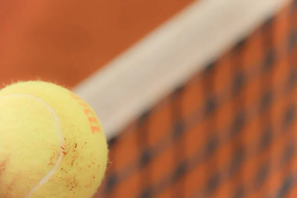 Tennisballen op rode baan met grijs net — Stockfoto