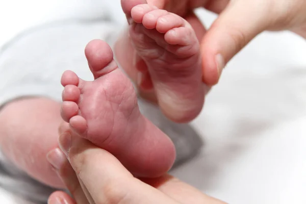 Pied de bébé dans les mains de la mère, nouveau-né petites jambes — Photo