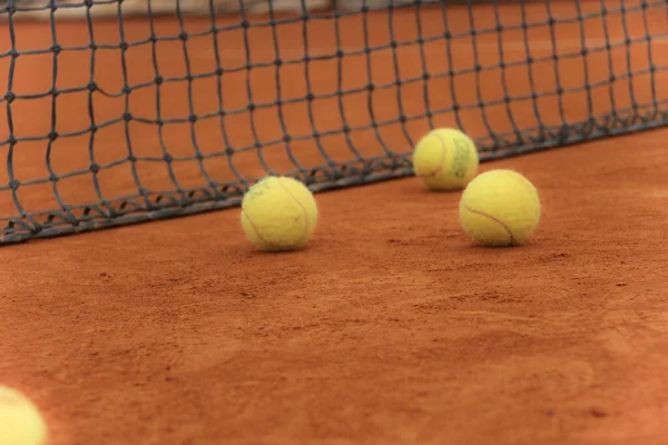 Tennisbollar på röd bana med grått nät — Stockfoto
