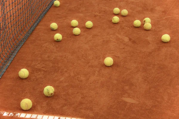 Tennisballen op rode baan met grijs net — Stockfoto