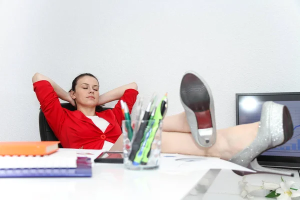 Relaxada e vencedora mulher de negócios sentada com as pernas na mesa — Fotografia de Stock