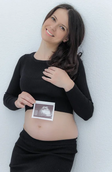 Счастливая беременная женщина с большим животом у окна, беременность, мать — стоковое фото