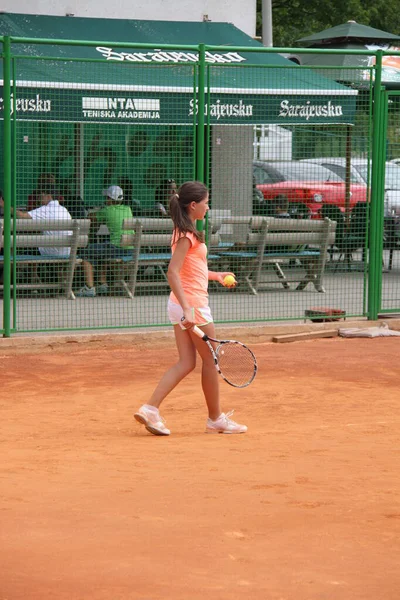 Krásná mladá dívka na otevřeném tenisovém kurtu hrát tenis — Stock fotografie