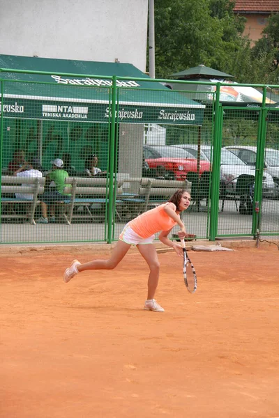 Beautiful young girl on open tennis court playing tennis — Stok fotoğraf