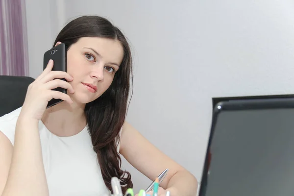 Mulher de negócios atraente usar telefone inteligente e sentado em sua wor — Fotografia de Stock