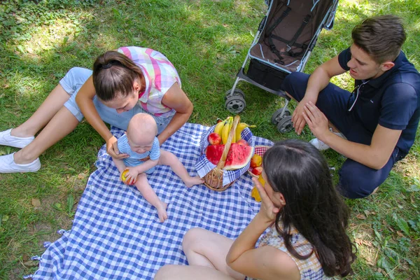 Família feliz fazendo um piquenique no parque verde — Fotografia de Stock
