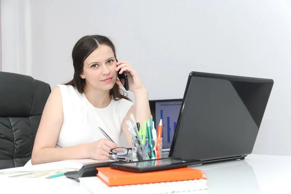 Çekici kadın kullanım akıllı telefon ve onun wor oturan — Stok fotoğraf