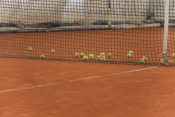 Tennisbollar på röd bana med grått nät — Stockfoto