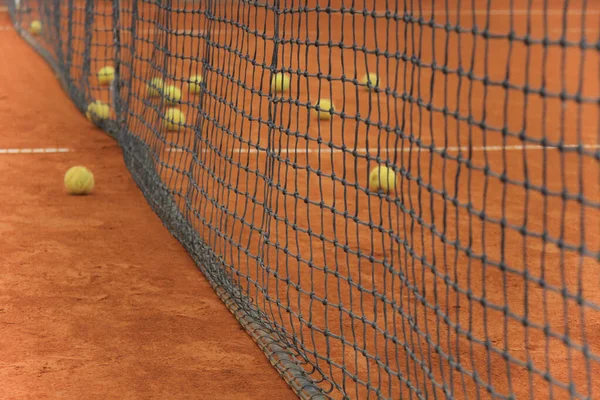 Tennisballen op rode baan met grijs net — Stockfoto