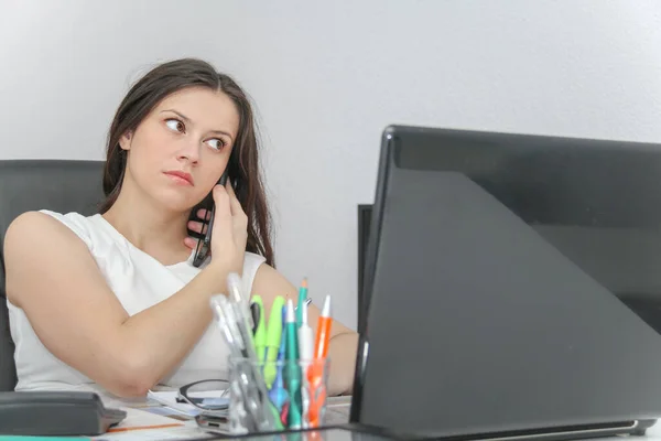 Atraktivní žena použití chytrý telefon a posezení na její práci — Stock fotografie