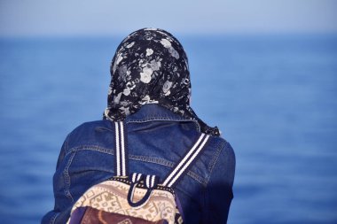 Genç bayanın arkası gün batımını izliyor ve fotoğraf çekiyor. 