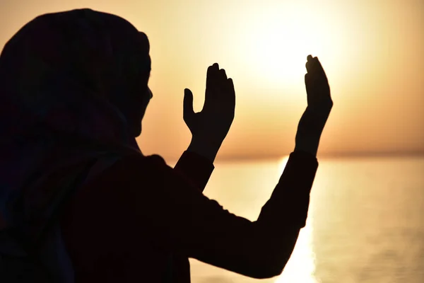 Silhueta de uma mulher muçulmana rezando durante o pôr do sol no grande sh — Fotografia de Stock
