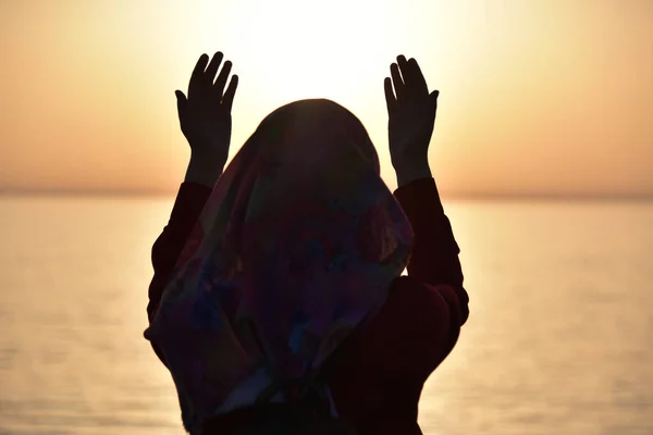 Silhueta de uma mulher muçulmana rezando durante o pôr do sol no grande sh — Fotografia de Stock