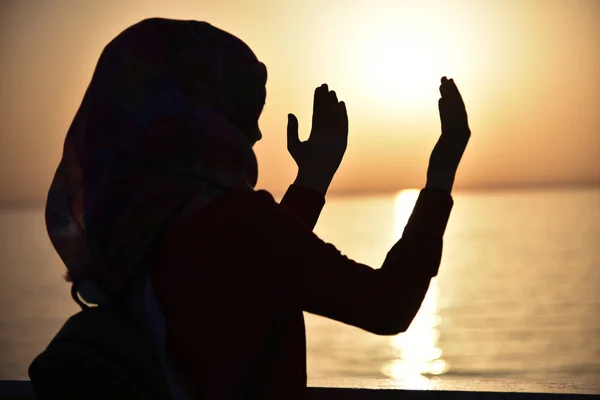 Siluet seorang wanita muslim berdoa selama matahari terbenam di sh besar — Stok Foto