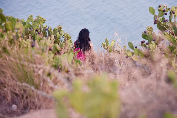 Akşam kumsalında taş üstünde oturan kadın, dalgalara bak ve dinle.