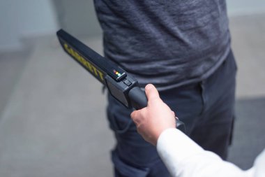 Metal detektörlü muhafız bir adamı silah ve metal için kontrol ediyor.