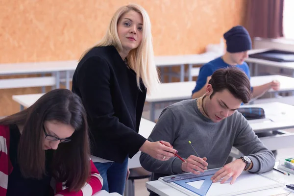 Όμορφη νεαρή δασκάλα βοηθά ένα μαθητή κατά τη διάρκεια του μαθήματος. Φ — Φωτογραφία Αρχείου