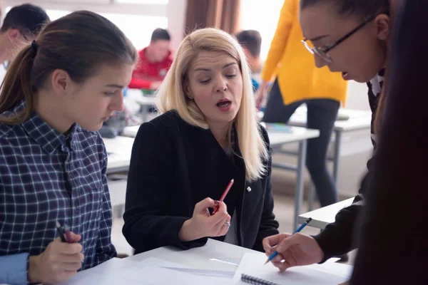 Belle jeune enseignante aidant un élève en classe. F — Photo