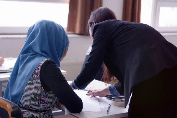 Belle jeune enseignante aidant un élève en classe. F — Photo