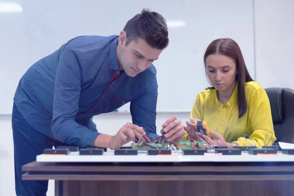 Két fiatal jóképű mérnök, akik elektronikai alkatrészeken dolgoznak.T — Stock Fotó