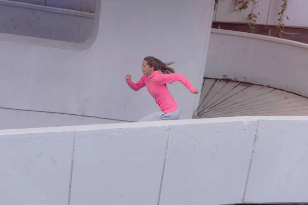 Ung kvindelig kvinde løber udendørs i byvejen. Ung kvinde - Stock-foto