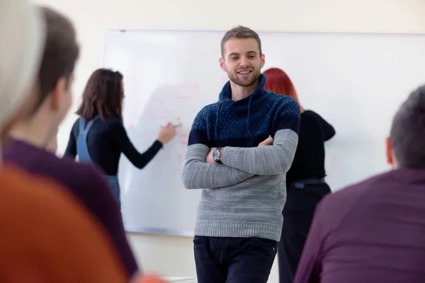 Jonge man economie professor uit te leggen les aan multi-etnische dekhengst — Stockfoto