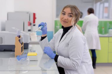 Laboratuvarda test tüpleriyle çalışan genç kadın laboratuvar bilim adamı.