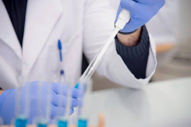 Laboratuvarda test tüpleriyle çalışan genç kadın laboratuvar bilim adamı.