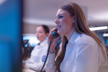Güvenlik görevlisi gözetleme odasındaki modern güvenlik kameralarını izliyor. Bir grup güvenlik görevlisi oturuyor ve izliyor..