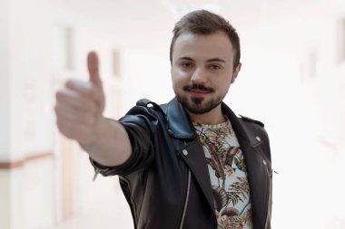 Gülümseyen, sakallı bir adamın portresi koridorda el hareketi yapıyor. 