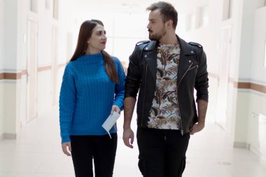 İki erkek ve kadın üniversite öğrencisi yürüyor ve konuşuyor.