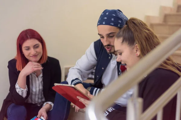 College life.Group of students learning  while sitting on stairs