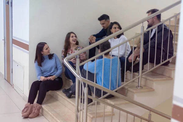 College life.Group of students learning  while sitting on stairs