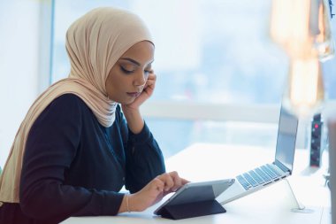 Genç Afrikalı Amerikalı iş kadını masasında oturuyor ve laptopuyla çalışıyor..