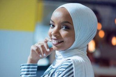 Genç Afrikalı Amerikalı iş kadını masasında oturuyor ve gülümsüyor..