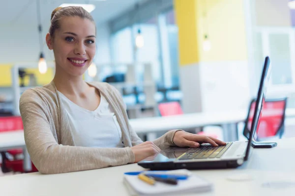 年轻的女商人在工作时使用笔记本电脑 下班后一个人呆着完成工作 看着镜头微笑 — 图库照片