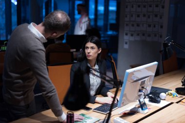 İki odaklanmış genç iş arkadaşı modern bir ofiste toplantı yaparken yeni bir proje hakkında konuşuyorlar.