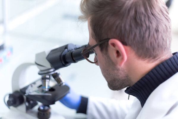 Microbiologist with a tube of biological sample contaminated by Coronavirus with label Covid-19 / doctor in the laboratory with a biological tube for analysis and sampling of Covid-19 infectious disea