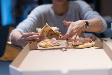 Güzel bir kadın pizza yiyip kola içerken gecenin geç saatlerinde Expres restoranında oturuyor..