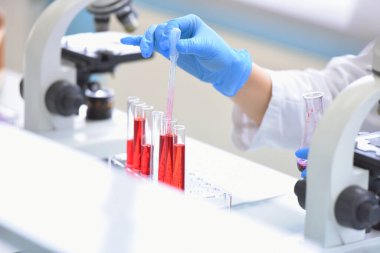 Laboratuvarda mikroskopla araştırma, mikrobiyolojik analiz ve tıp yapan genç bir kadın bilim adamı..