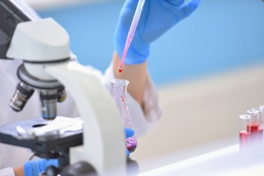 Laboratuvarda mikroskopla araştırma, mikrobiyolojik analiz ve tıp yapan genç bir kadın bilim adamı..