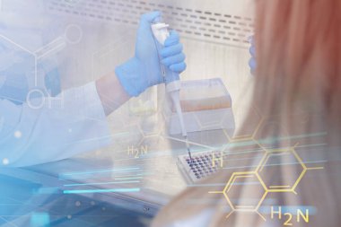 Laboratuvarda test tüpleri ve mikroskop ile çalışan iki genç laboratuvar bilim adamı klinik laboratuarında test veya araştırma yapıyor. Bilim, kimya, biyoloji, tıp ve insan konsepti.