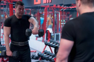 Çekirdek Vücut Geliştirme. Kas geliştiren vücut geliştirici beden eğitimi modeli. Spor salonunda dambılları olan kollar. Spor salonundaki egzersizlerin konsept fotoğrafı