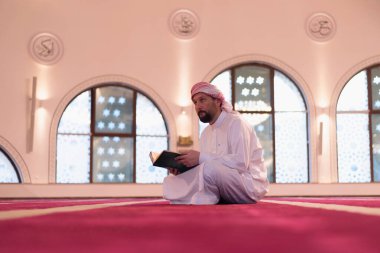 Genç Arap Müslüman adam Kuran okuyup dua ediyor. Camide Kur 'an okuyan dindar Müslüman adam..